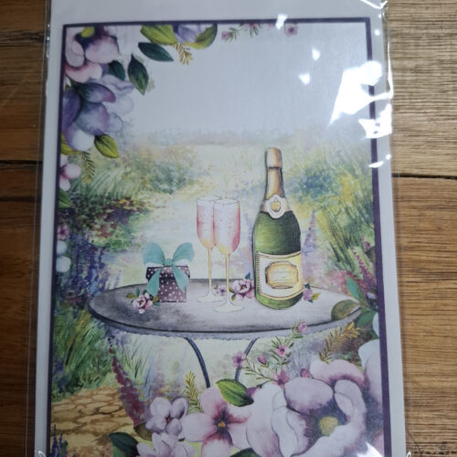 engagement card showing champagne and glasses on a garden table