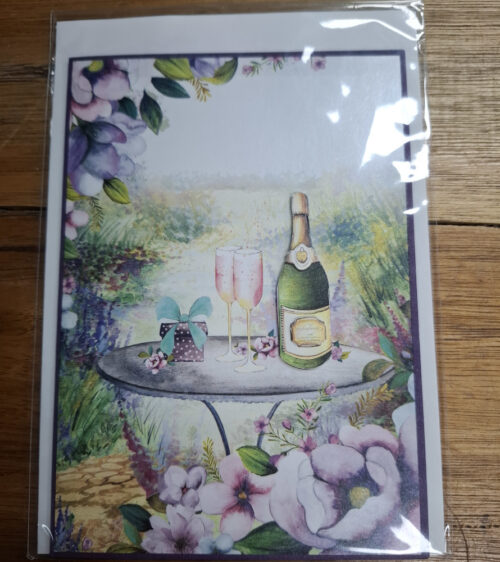 engagement card showing champagne and glasses on a garden table